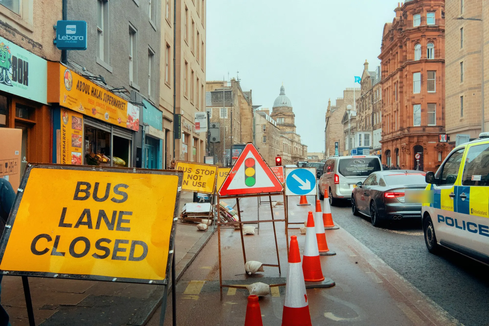 Bus lane closed signs, temporary traffic signals and cones on a city street