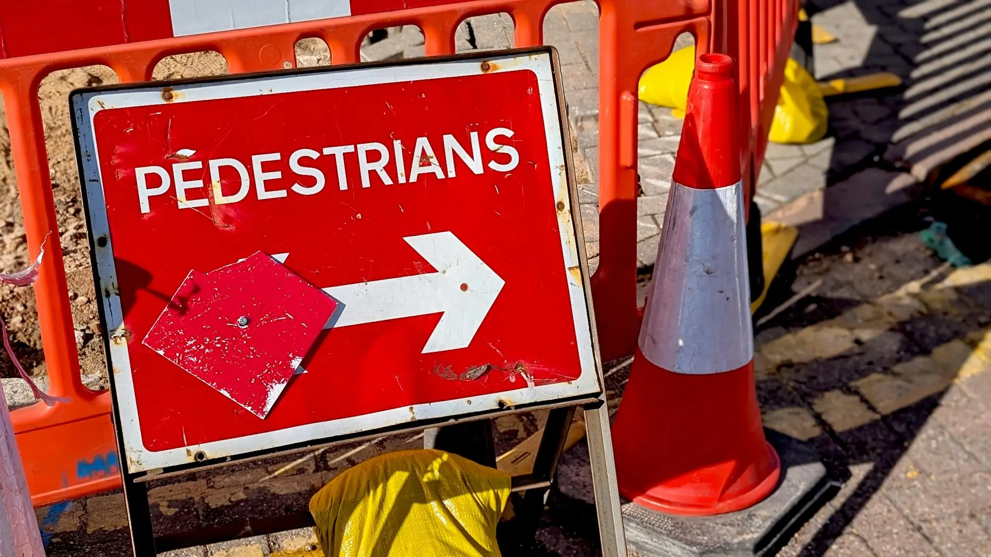 Pedestrian diversion sign and barriers around a footway excavation